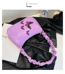 Detail of purple shoulder bag featuring butterfly print and ruched handle design