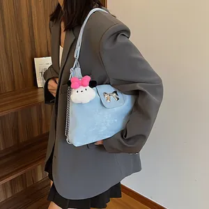 Light blue crossbody bag with silver bow detail and plush charm in a lifestyle setting