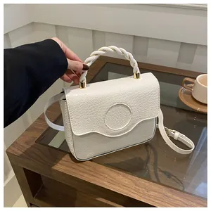 Detail of white crocodile-embossed handbag with woven handle and gold-tone hardware
