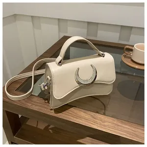Sac carré à motif litchi avec boucle lune argentée sur une table en bois