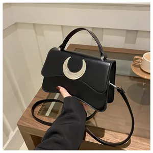 Détail du sac noir grainé avec boucle de lune argentée et rabat aux lignes ondulées