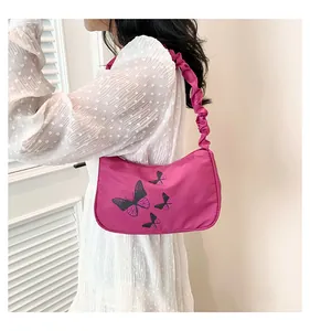 Detailed view of rose red butterfly print shoulder bag with ruched strap on a model