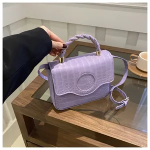 Detail of lavender crocodile texture handbag featuring unique twisted rope handle and gold hardware
