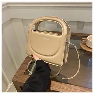 Close-up of minimalist beige PU leather handbag featuring embossed white fashion lettering