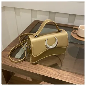 Détail d'un sac à main doré chic avec boucle en croissant sur une table en bois