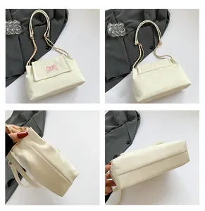 Vue détaillée du sac crème avec broderie papillon rose et bandoulière en chaîne dorée