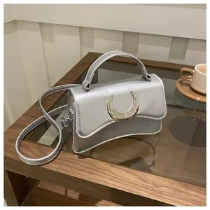 Vue détaillée du sac bandoulière argenté avec sa boucle chic en forme de croissant