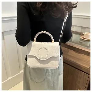 Detail of a cream crocodile embossed handbag with a woven handle in a cozy cafe setting