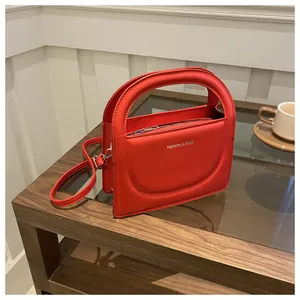 Close-up of bright red PU leather handbag with elegant circular handle and silver logo