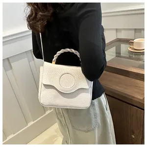 Detail of white crocodile pattern handbag with unique braided handle on a female model