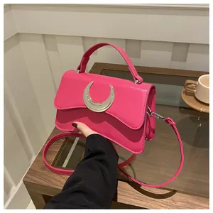 Détail du sac bandoulière fuchsia à texture litchi et boucle en croissant argentée