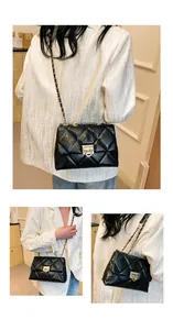 Detail of black quilted leather shoulder bag with gold chain strap and metal lock