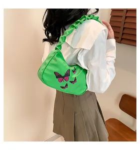 Detail of green butterfly nylon bag with pleated strap worn by a model in casual style