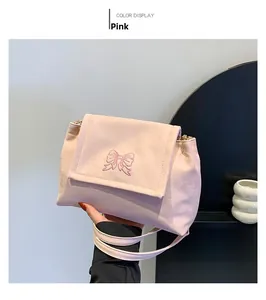 Détail de la broderie papillon rose et texture satinée sur le sac à bandoulière