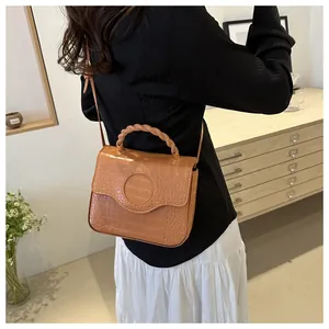 Detailed back view of a brown crocodile pattern crossbody bag with woven handle