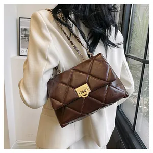 Detail of dark brown quilted crossbody bag with gold metallic lock and chain strap