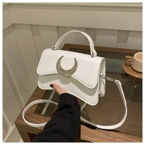 Détail d'un sac à bandoulière blanc motif litchi avec boucle en lune argentée