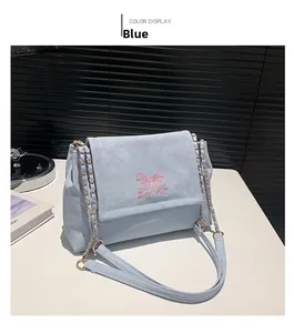 Détail du sac à chaîne bleu clair avec broderie papillon rose et bandoulière dorée