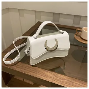 Détail d'un sac blanc en cuir avec boucle lune argentée sur une table en bois