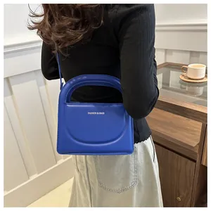 Blue crossbody bag with semi-circular handle shown in a lifestyle street style shot