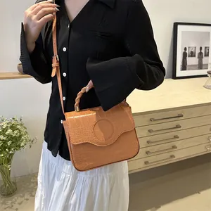 Orange-brown crocodile pattern handbag with braided handle shown in minimalist home setting