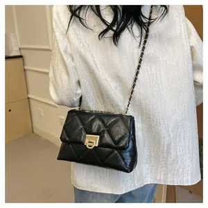 Detail of black quilted crossbody bag with gold chain strap and metal turn-lock closure