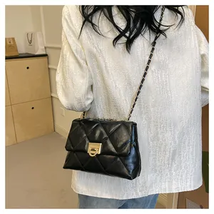 Detail of a black quilted chain crossbody bag styled on a white textured blazer