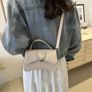Sac bandoulière blanc crème avec boucle lune argentée porté par un mannequin