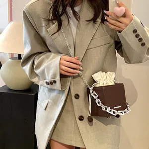 Chic dark coffee cube crossbody bag with silver chain strap shown in a fashion outfit