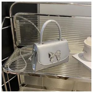 Detail of silver metallic square bag with 3D bow decoration and sleek top handle