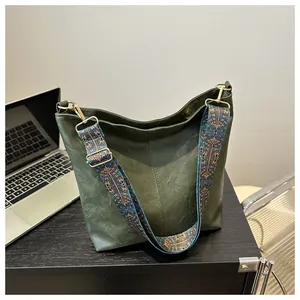 Detail of dark green tote bag featuring a textured finish and bohemian wide shoulder strap