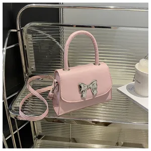 Detail of pink faux leather crossbody bag with a metallic silver bow on a metal rack