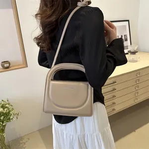 Minimalist beige leather shoulder bag with circular handle and fashion engraving