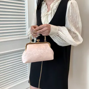 Sac de soirée rose en jacquard avec motifs floraux, cadre doré et bandoulière