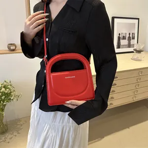 Fashionable red leather crossbody bag with top handle and white text for casual women's style