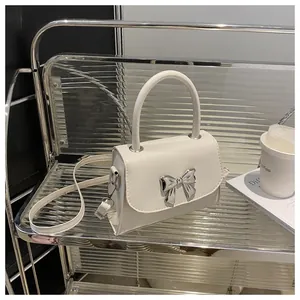 Detailed view of silver bow clasp on a minimalist white crossbody handbag for women