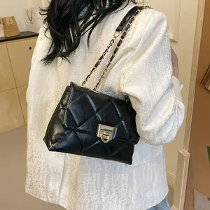 Elegant black quilted crossbody bag with gold chain strap shown on a model