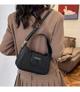Vue arrière du modèle portant un sac bandoulière noir en cuir PU avec lettrage doré
