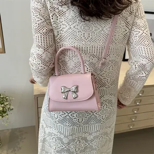 Pink mini crossbody bag with silver bow accent and leather handle for women