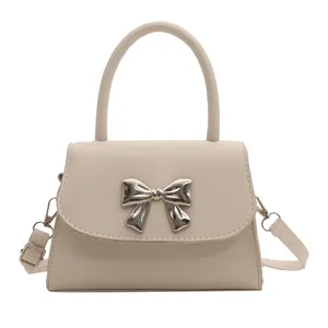 Chic cream white PU leather handbag with metallic bow accent and adjustable shoulder strap