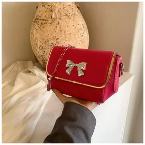 Close-up of red quilted crossbody bag featuring a silver bow buckle and metal chain strap