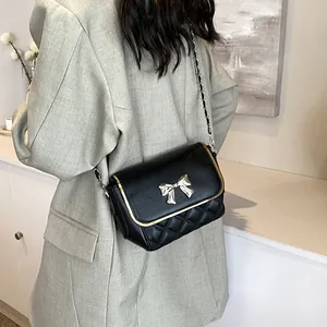 Quilted crossbody bag in black with golden trim and bow-shaped metal buckle detail