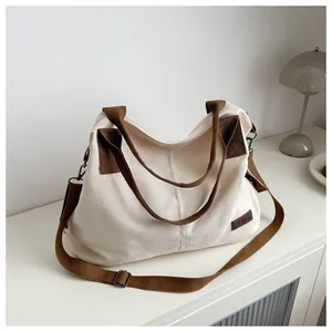 Detail of canvas bag with leather handles, fashion tag, and adjustable strap