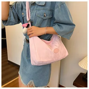 Close-up of light pink nylon crescent bag with adjustable wide strap and cute charm detail