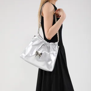 Metallic silver pleated crossbody bag with metal butterfly and chain strap on model
