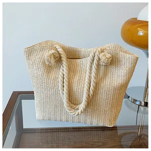 Détail du sac cabas en paille tissée avec poignées en corde et franges sur bureau chic