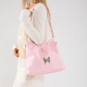 Elegant light pink shoulder bag with silver butterfly buckle and chain strap shown on model