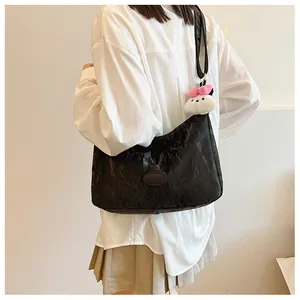 Detail of black pleated shoulder bag with a cute white plush bear charm accessory