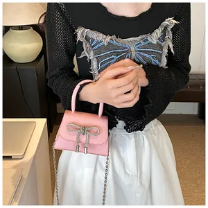 Detail van roze mini-tas met lychee-textuur, fonkelende strass-strik en zilveren ketting