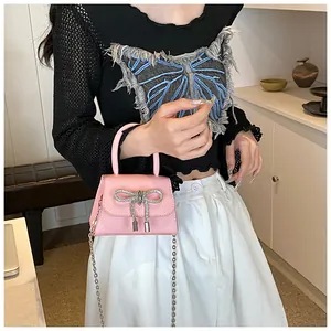 Detailopname van roze mini-tas met strass-strik en zilveren metalen kettingriem
